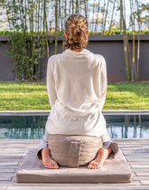 A person using a meditation cushion from the meditation kit collection.